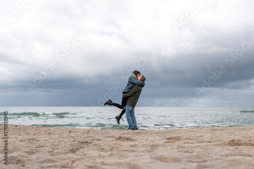 Russia, Kaliningrad Oblast, Zelenogradsk, Adult couple kissing on sandy coastal beach of Baltic Sea photo