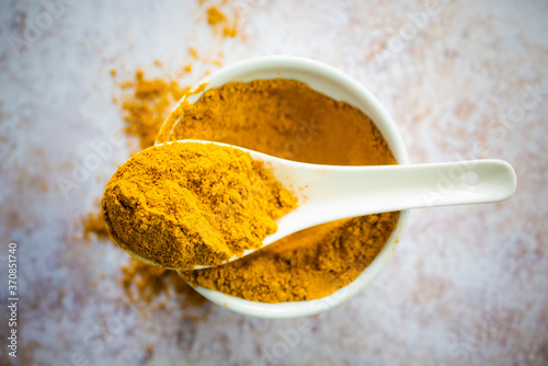 Bowl and spoon of yellow curry powder photo