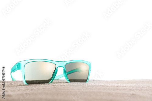 Stylish sunglasses on sand against white background. Space for text