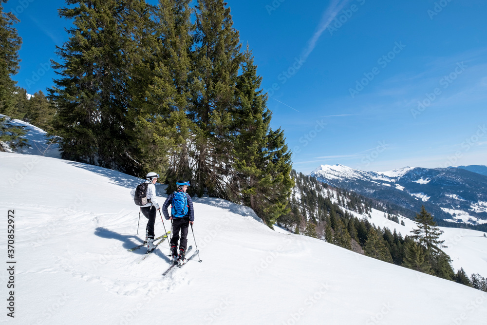Mother and son skiing on snowy mountain against sky, Berchtesgaden, Bavaria, Germany