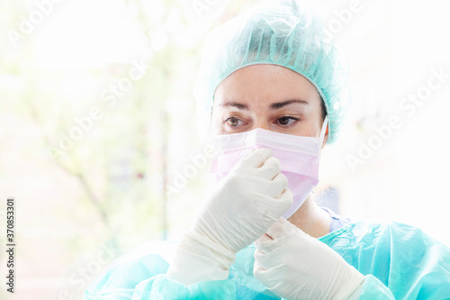 Close-up of female nurse wearing surgical mask against window in hospital photo