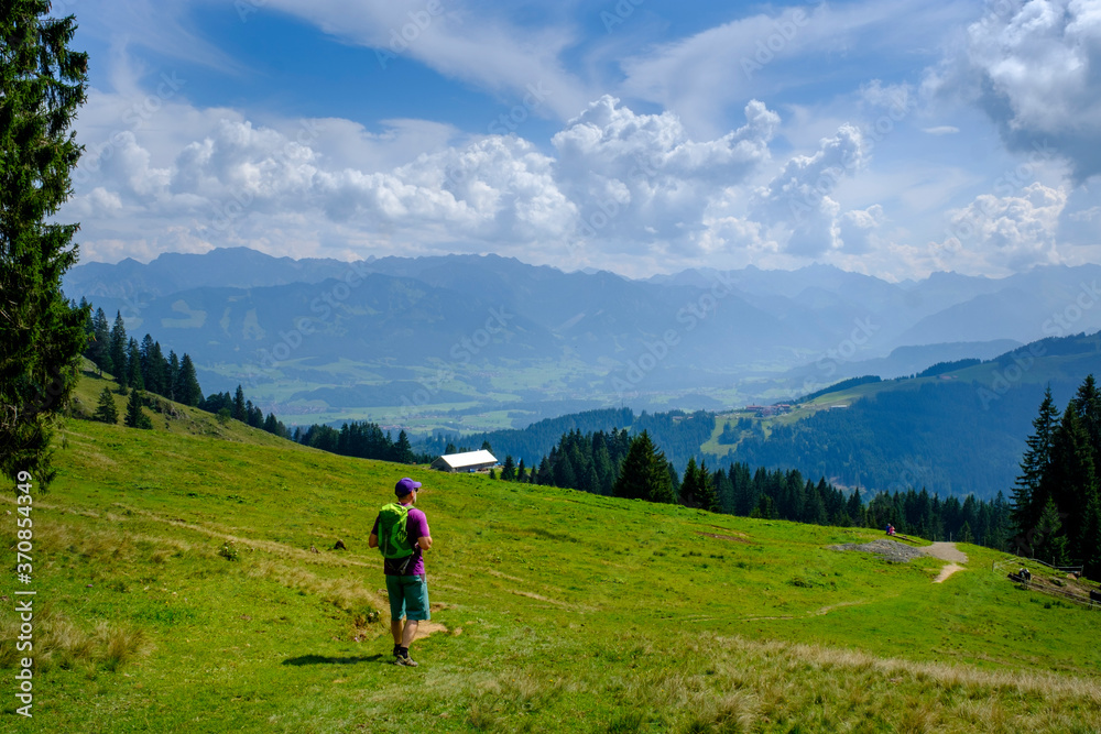 Germany, Bavaria, Immenstadt, Lone hiker taking break to admire scenic landscape of Allgau Alps Germany, Bavaria, Immenstadt, Lone hiker taking break to admire scenic landscape of Allgau Alps