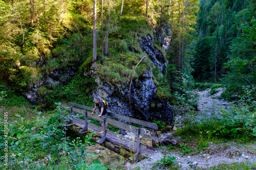 Austria, Tyrol, Steinberg am Rofan, Male backpacker admiring surrounding mountain forest from small narrow bridge photo