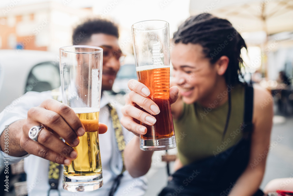 Happy young couple clinking beer glasses outdoors at a bar Happy young couple clinking beer glasses outdoors at a bar