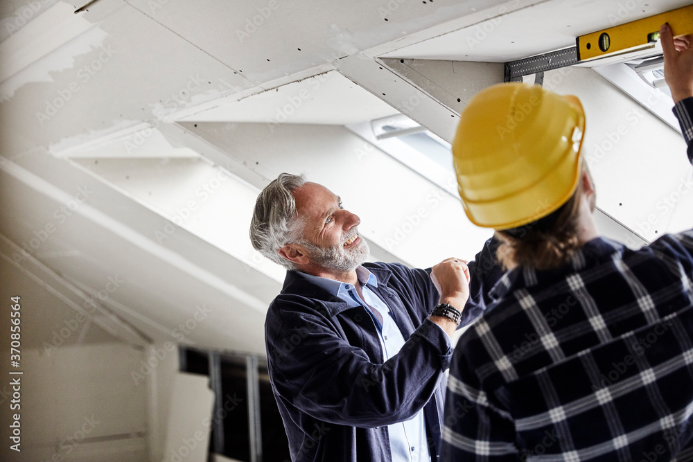Architect and worker measuring window on a construction site Architect and worker measuring window on a construction site