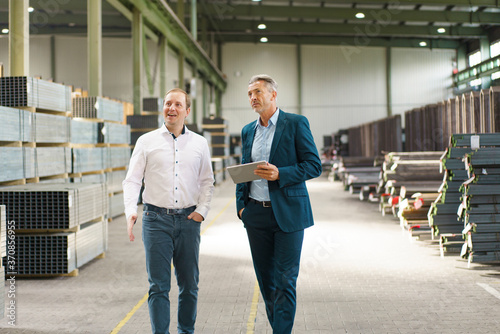 Two businessmen having a meeting and walking in a factory photo