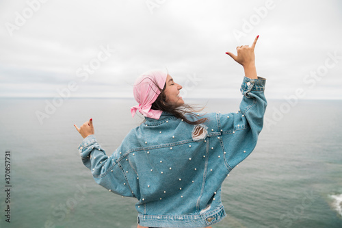 Female cancer survivor smiling and dancing against sea photo