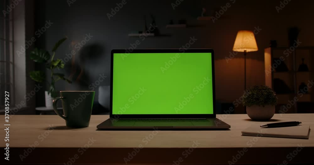 Close up shot of modern chroma key green screen laptop computer set up for work on desk at night - remote work, technology concept 4k video template