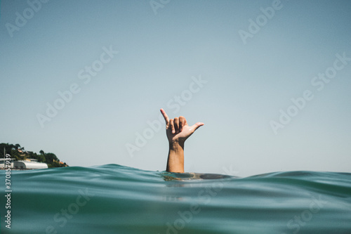 Womans hand making surfer's sign in water photo