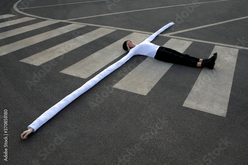 Woman with long artificial hands lying on crosswalk