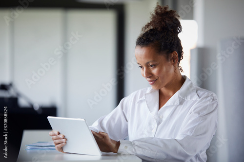 Portrait of smiling businesswoman using digital tablet in modern office