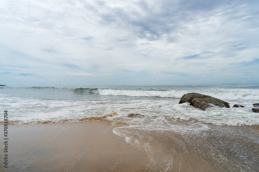 Waves and large rocks on the beach. cloudy sky, Arugam Bay, Sri Lanka