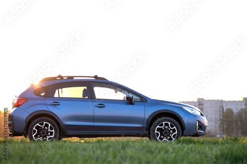 Landscape with blue off road car on green grass. Traveling by auto, adventure in wildlife, expedition or extreme travel on a SUV automobile. Offroad 4x4 vehicle in field at sunrise. © bilanol