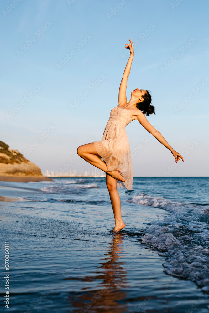 Delicate ballerina dancing on the beach at sunset Delicate ballerina dancing on the beach at sunset