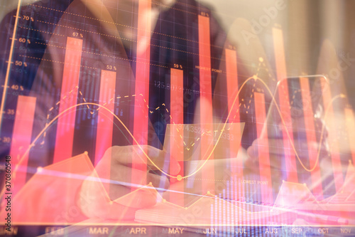 Double exposure of man's hands holding and using a phone and financial graph drawing. Analysis concept.