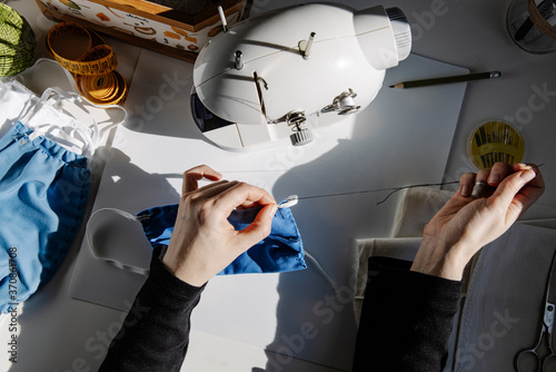 From above talented female artisan sewing piece of rubber band while working in studio photo