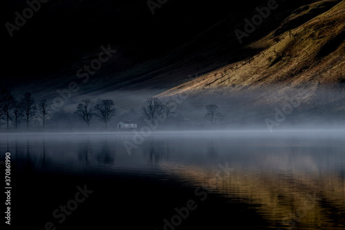 Dawn mist rises around Buttermere, the lake in the English Lake District in North West England. The adjacent village of Buttermere takes its name from the lake. Historically in Cumberland, the lake is now within the county of Cumbria. It is owned by the National Trust, forming part of its Buttermere and Ennerdale property photo