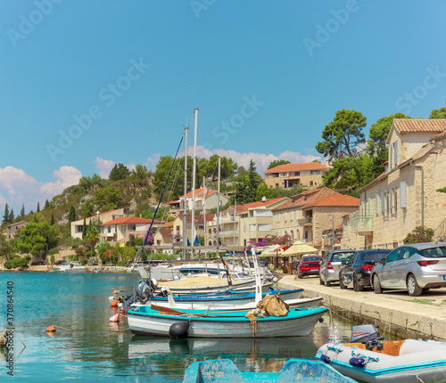 Waterfront view of a tiny village of Bobovisca on the island of brac. Crystal clear teal and green water reflection the bright sky. Small boats docked in the harbour