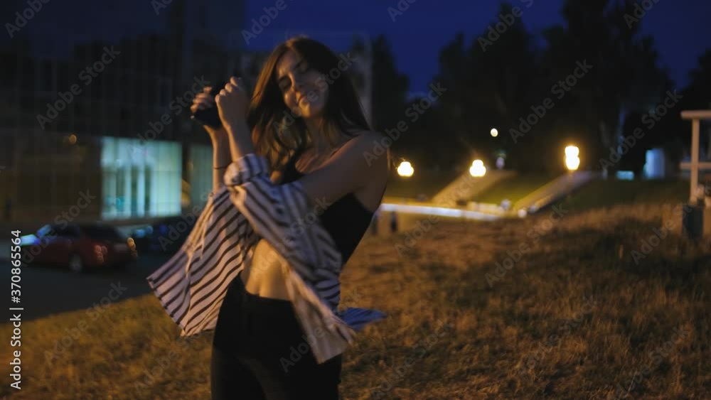 Young attractive redhead hipster woman dance on street at night. Young attractive redhead hipster woman dance on street at night.