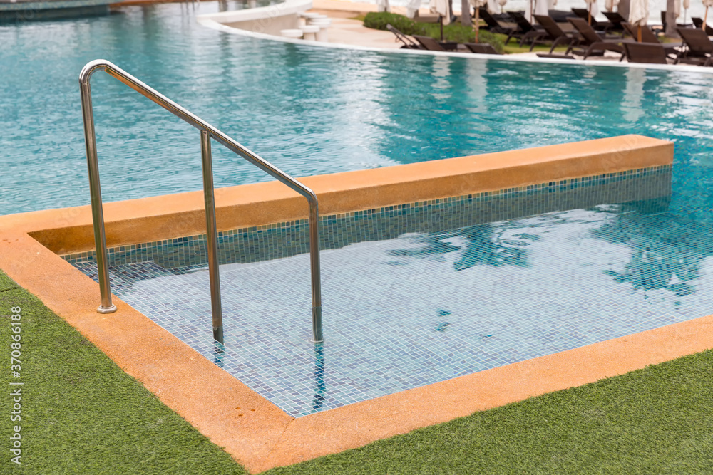 Ladder stainless handrails for descent into swimming pool. Swimming pool with handrail . Ladder of a swimming pool. Horizontal shot.