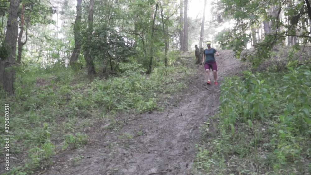 The topic of weight loss and excess weight. A plump woman runs in the forest along a path. Diet sports and a healthy lifestyle. Overweight female running in a wood. Burn fat in cardio workout The topic of weight loss and excess weight. A plump woman runs in the forest along a path. Diet sports and a healthy lifestyle. Overweight female running in a wood. Burn fat in cardio workout