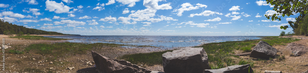 Coastline panorama. seascape with horizon line. sky with clouds. stones on the shore