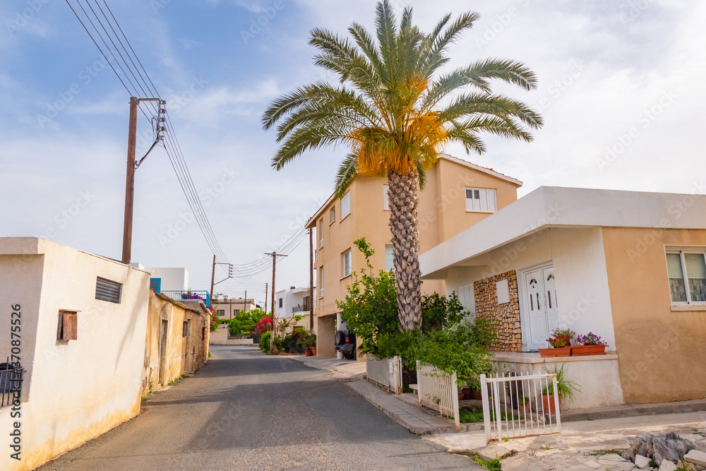 Cyprus. The streets of the village of Kouklia. Small houses stand along the road in Cyprus. A palm tree grows next to a one-story house. Kouklia village on a summer day. A trip to Cyprus.