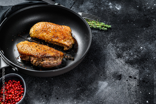 Grilled duck breast fillets in a frying pan. Black background. Top view. Copy space