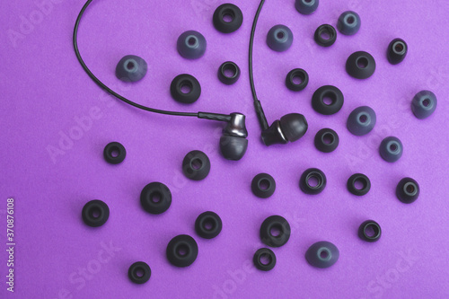 Earphones between of ear cushions on purple background. in-ear headphones and lot of embouchures photo