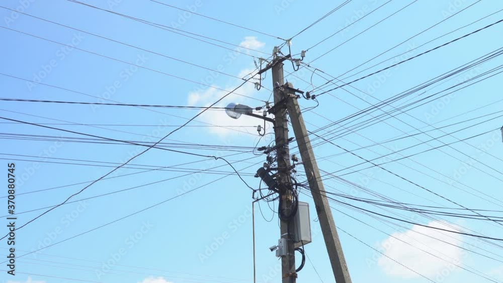 Chaotically connected electrical and optical wires on a reinforced concrete support. Lots of wires on one pole