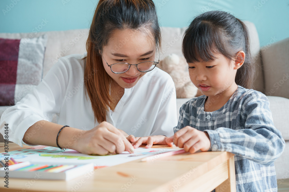 Happy family with mother and daughter doing homework together at home Happy family with mother and daughter doing homework together at home