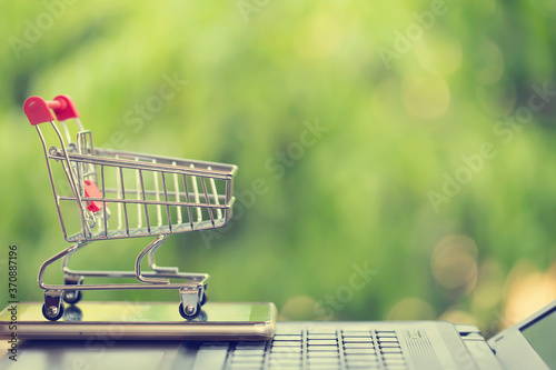 Foto Online marketing and payment concept: Shopping cart with smartphone on laptop computer and icon online shopping and social media networking