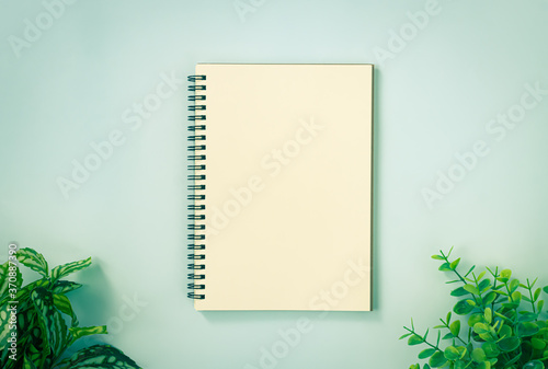 Spiral Notebook or Spring Notebook in Unlined Type and Office Plants at Bottom on Blue Pastel Minimalist Background in Vintage Tone