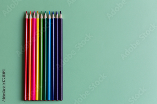 Back to school concept with colorful pencils on green background, copy space