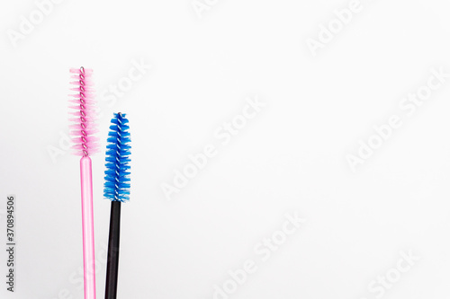 Eyelash brush on white background. Blue, black and soft pink eyelash brush for girl master eyelash extension. Professional makeup tools for eyelashes and eyebrows. Concept for Beauty salon and care