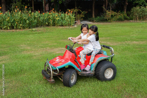 Asian girls enjoy driving ATV on the green grass field © yupin