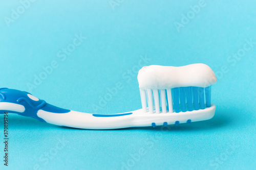 Blue toothbrush with toothpaste on blue background with copy space