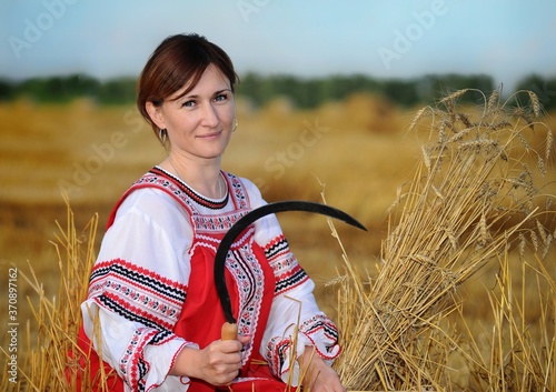 Peasant girl in national costume on the field during the harvest