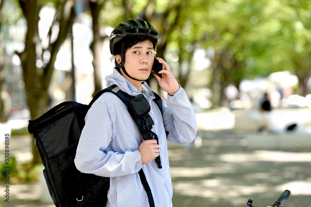 電話をするデリバリーの配達員の男性 電話をするデリバリーの配達員の男性