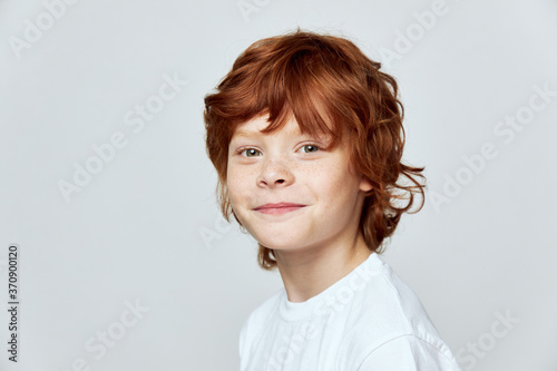 Red-haired boy on a gray background smile white t-shirt cropped 