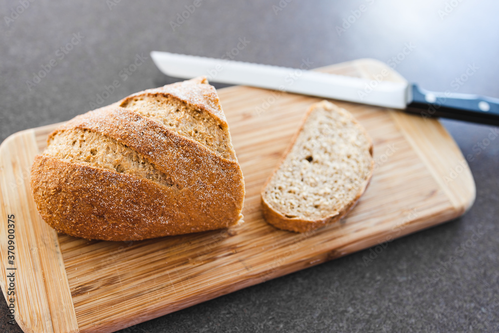 simple food ingredients, wholegrain rye bread on cutting board with bread knife next to it simple food ingredients, wholegrain rye bread on cutting board with bread knife next to it