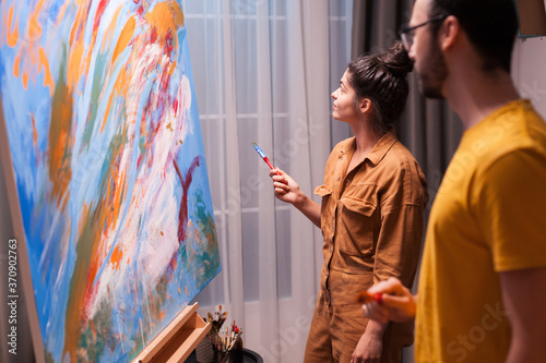 Couple of artist in art studio working on large painting. Modern artwork paint on canvas, creative, contemporary and successful fine art artist drawing masterpiece