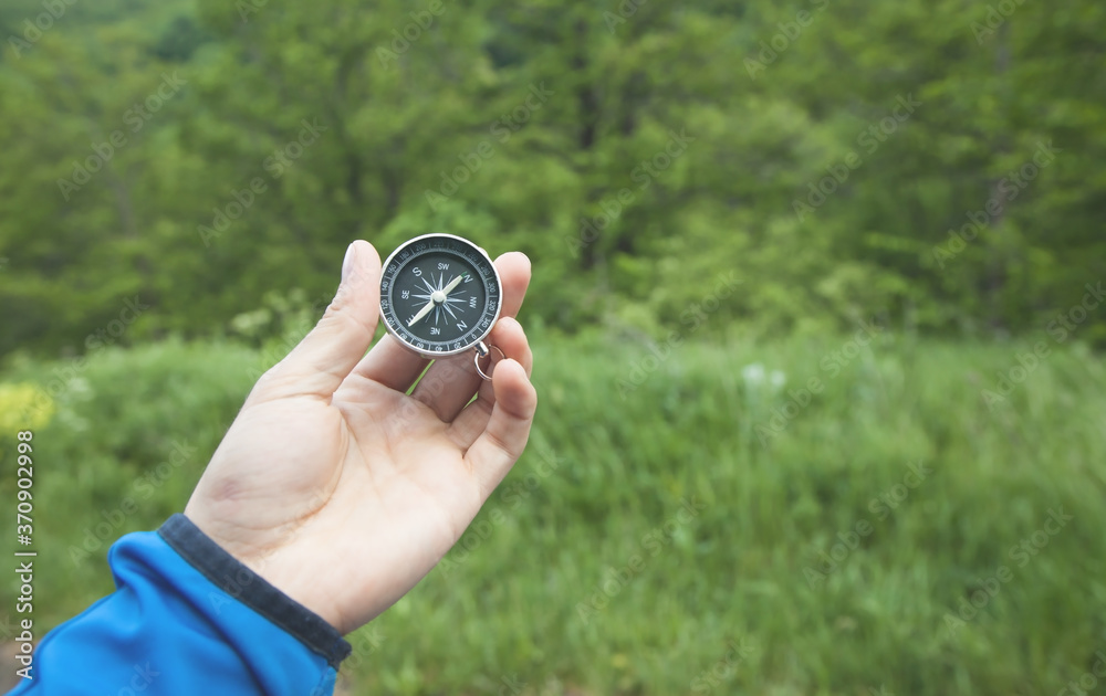 Male hand showing compass in forest. Male hand showing compass in forest.