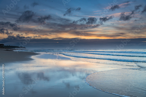 Sunrise seascape with cloud reflections on the beach