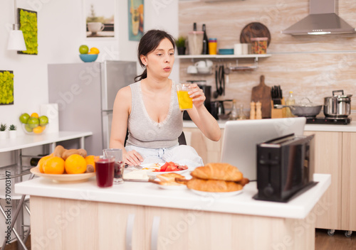 Woman making online shopping in the morning during breakfast paying with credit card. Entering information, customer using e-commerce technology buying stuff on the web, cosumerism banking and
