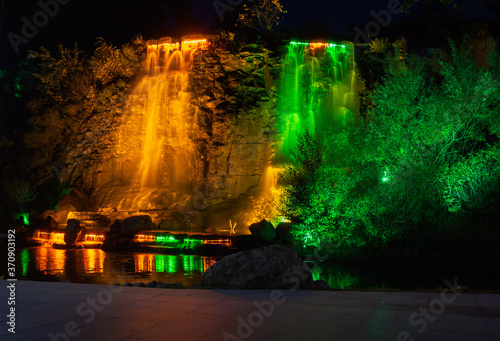 Night fonan in colorful lights, falling jets of water in a park