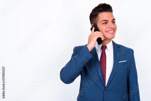 Portrait of happy young handsome multi ethnic businessman in suit talking on the phone