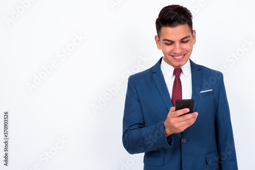 Portrait of happy young handsome multi ethnic businessman in suit using phone