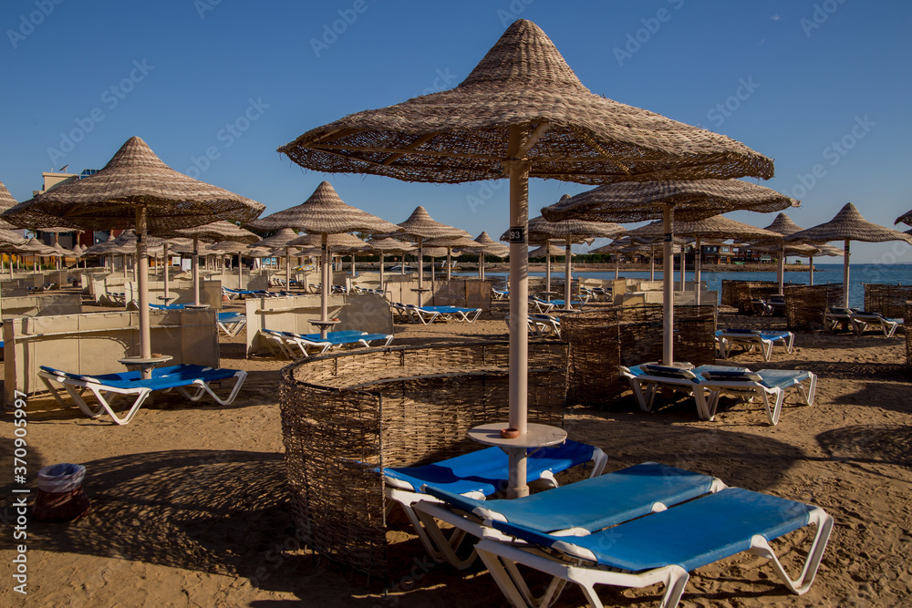 sandy beach with sun loungers thatched umbrellas