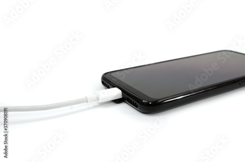 USB cable for smartphone and black smartphone on a white background. Close-up. Charge your phone.